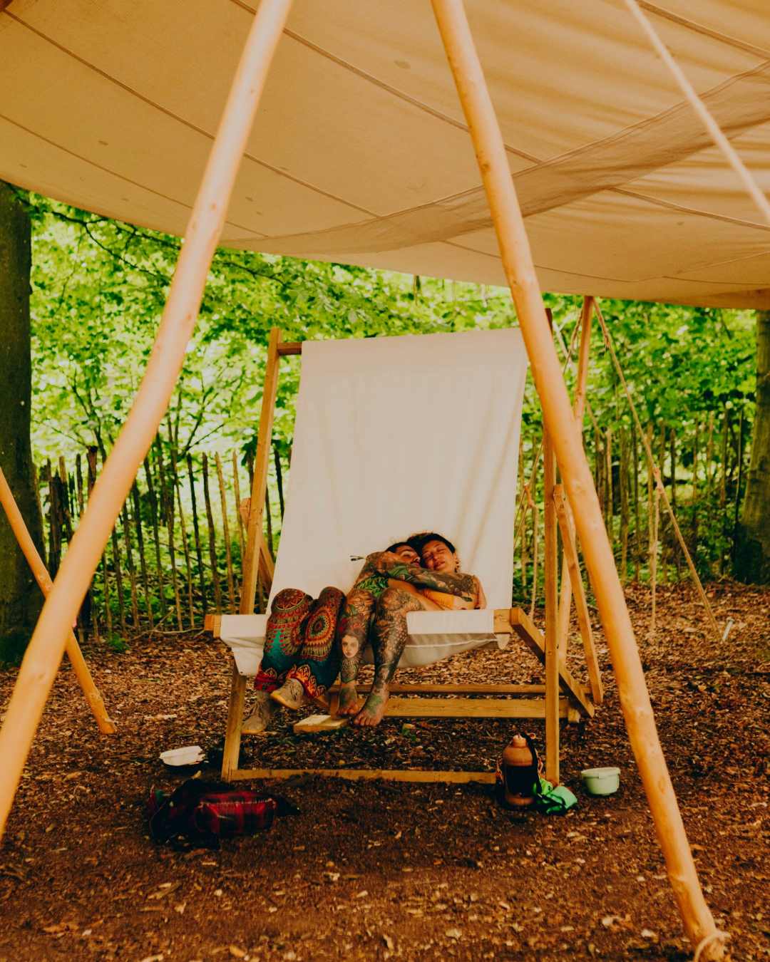 Picture of people relaxing in a wooded area on a oversized deck chair.