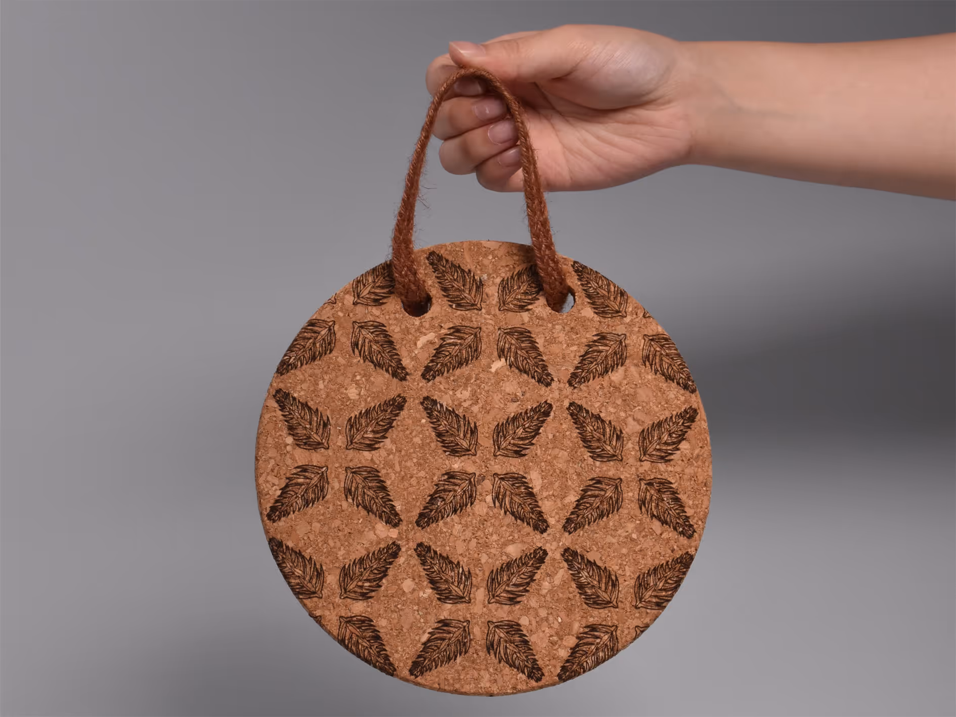 A laser-engraved Araucaria tree node pattern on a cork coaster, forming a symmetrical snowflake.