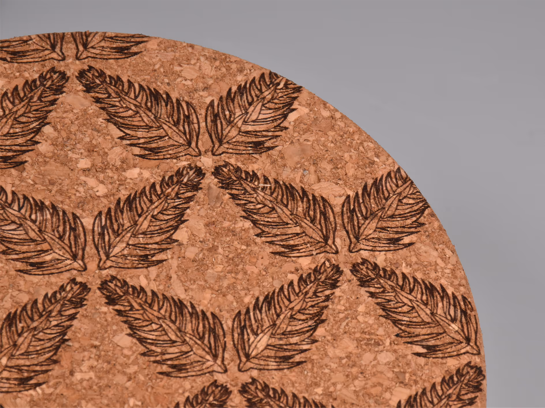 A laser-engraved Araucaria tree node pattern on a cork coaster, forming a symmetrical snowflake.