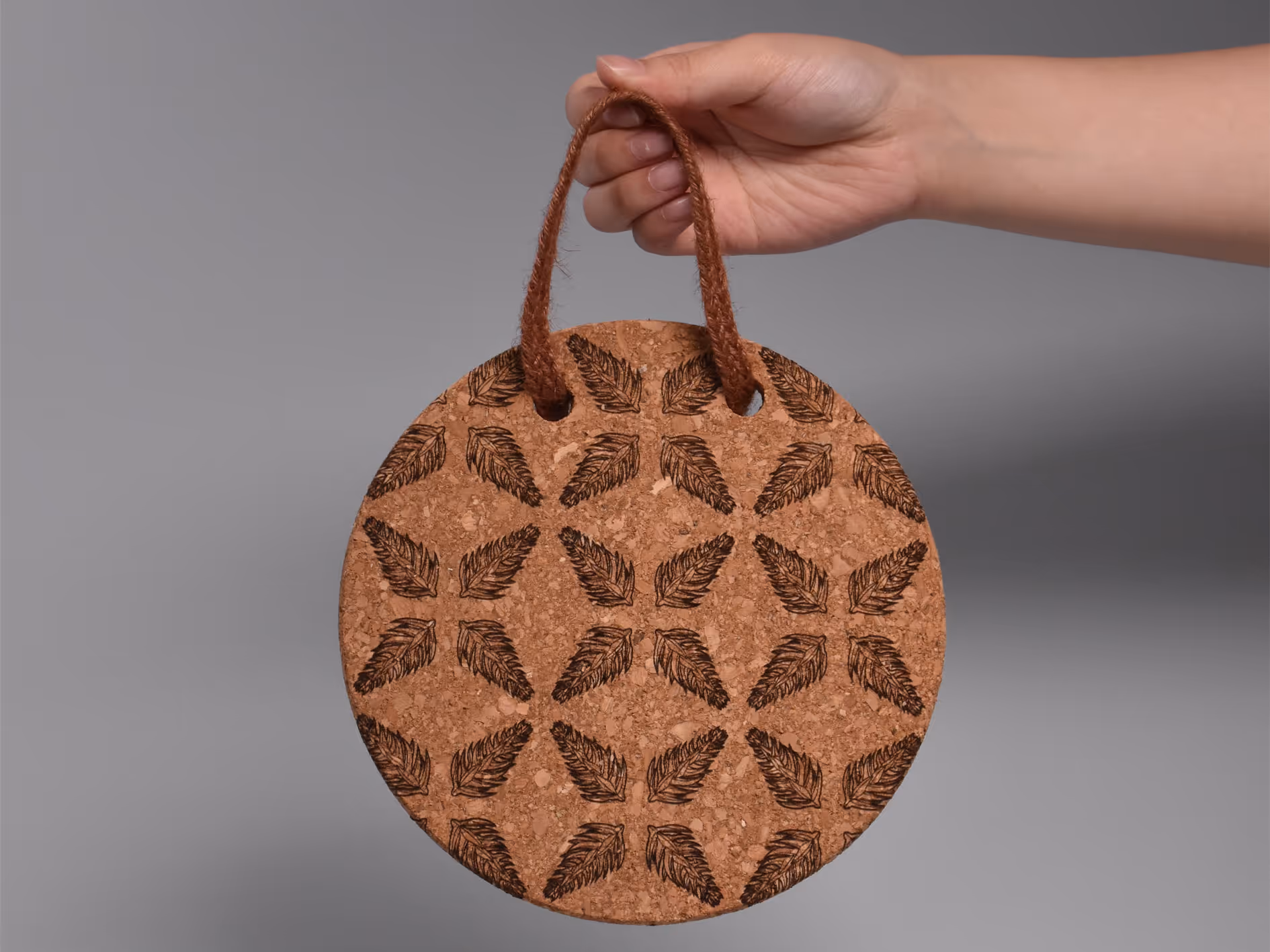 A laser-engraved Araucaria tree node pattern on a cork coaster, forming a symmetrical snowflake.
