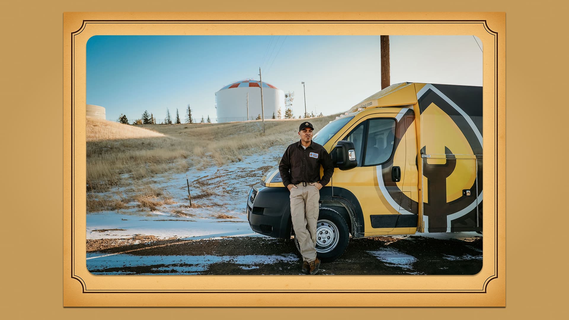 Travis James of Aspen Mountain Plumbing standing beside the company van near Cheyenne water storage tanks.