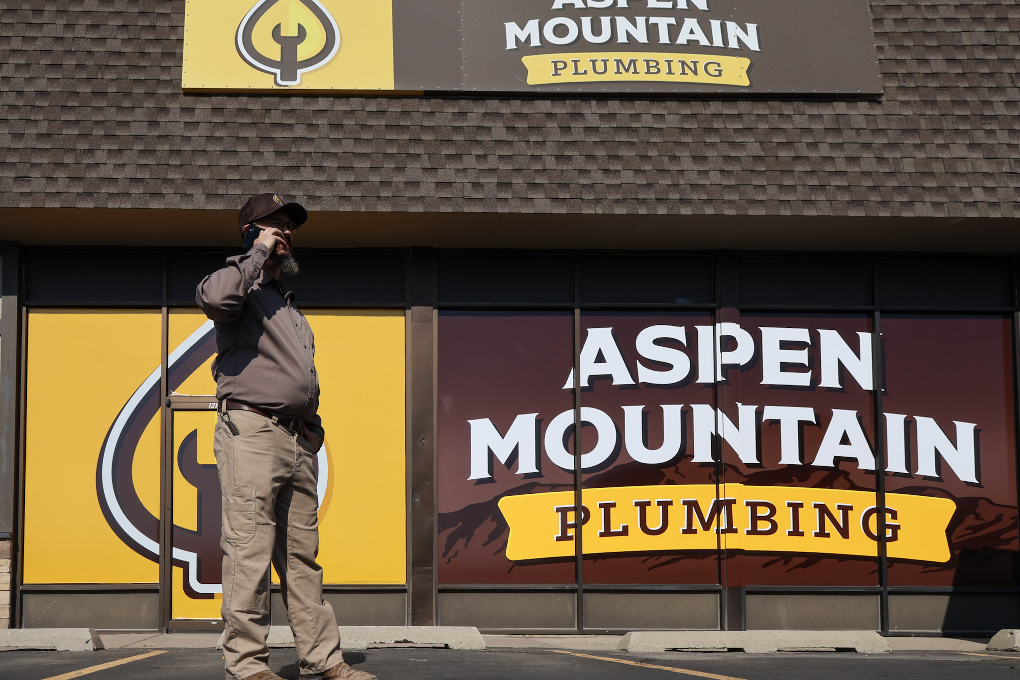 Owner Lance Ball taking a customer call outside the Aspen Mountain Plumbing storefront in Wyoming.