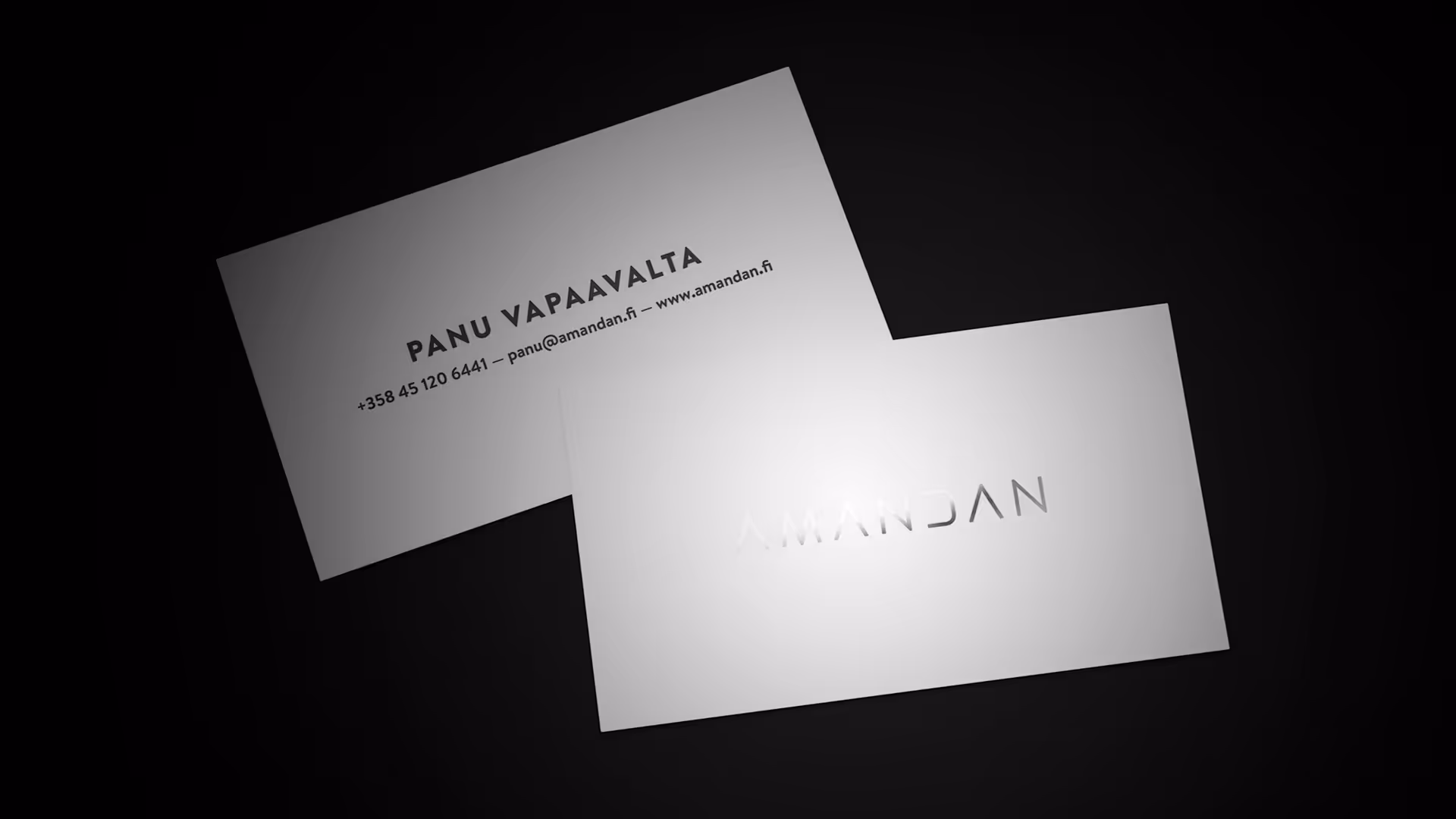Valkoiset käyntikortit, jossa tekstit ovat mustalla ja kääntöpuolella logo on hopeoitu.
