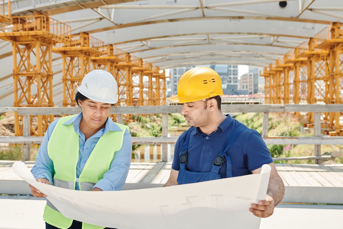 Two engineers reviewing construction plans at an active site.