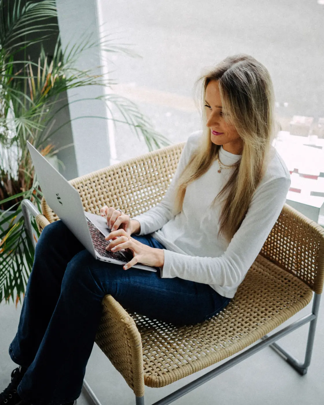 Synne hos Cure jobber på laptop i et avslappet miljø, representerer fleksibilitet og kundesentrert arbeid.