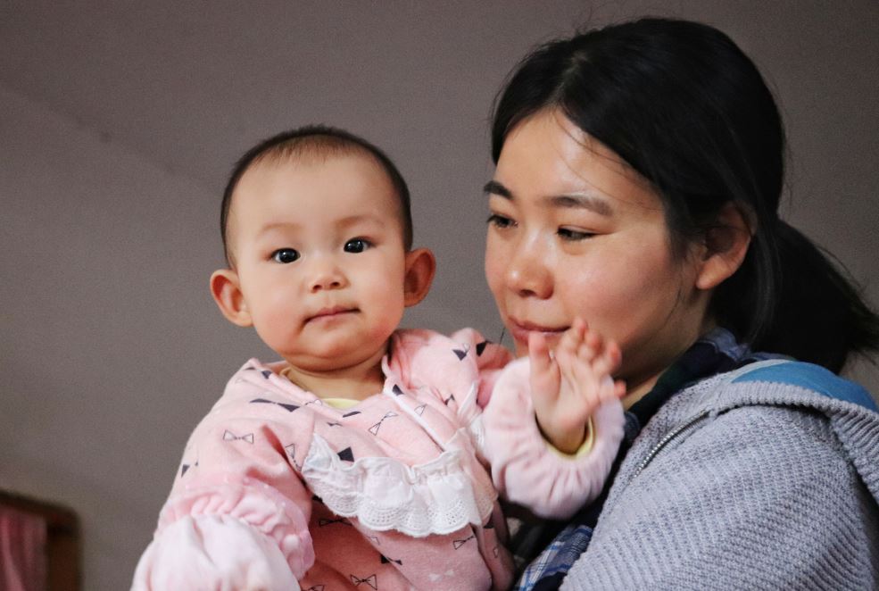 A mother holds up her young child.
