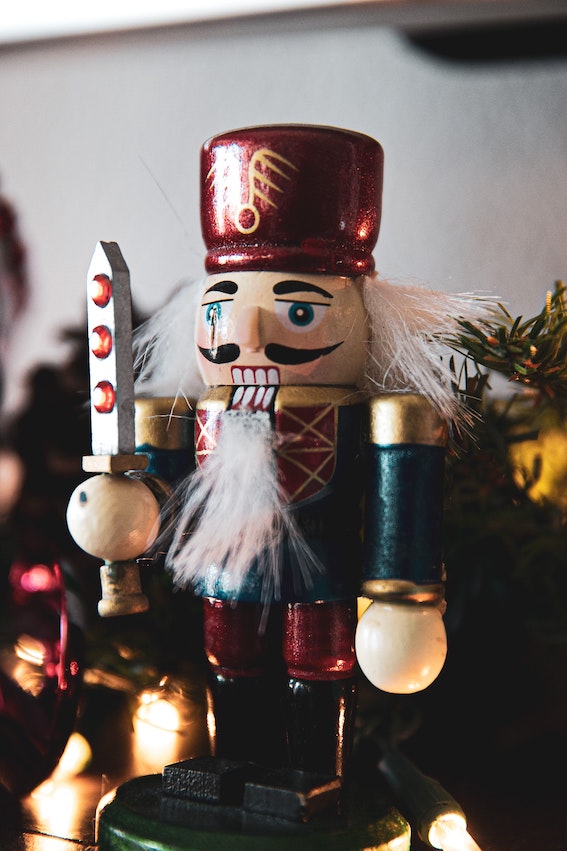 Wooden nutcracker surrounded by twinkle lights and pine boughs