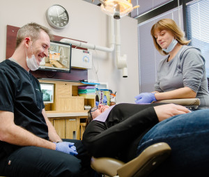 Two Winnipeg Dentists sit beside a patient in a dental chair before they fill a cavity.