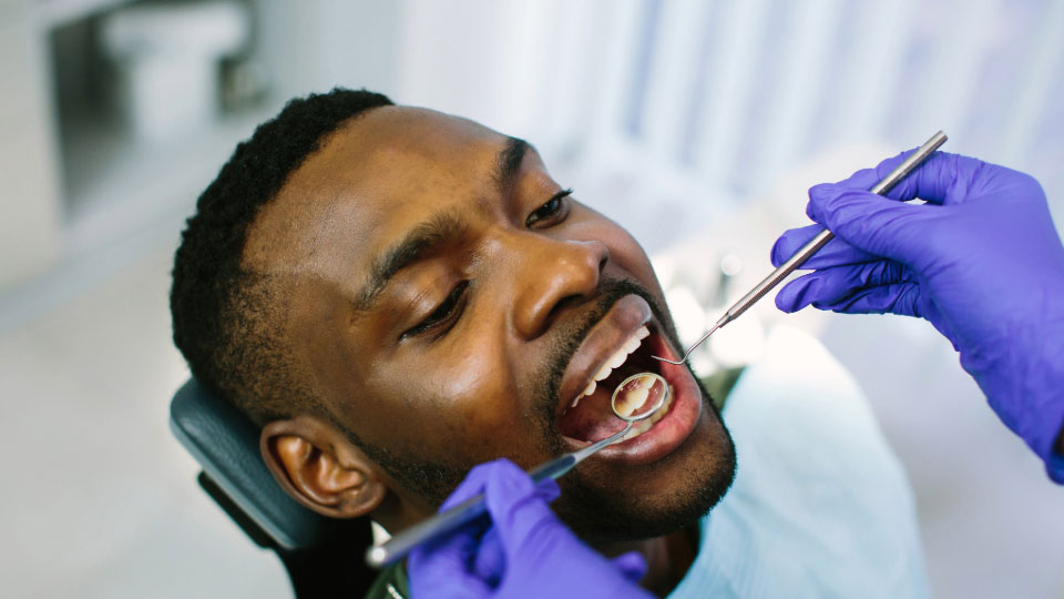 A man in a dental chair being examined by a dentist off-screen