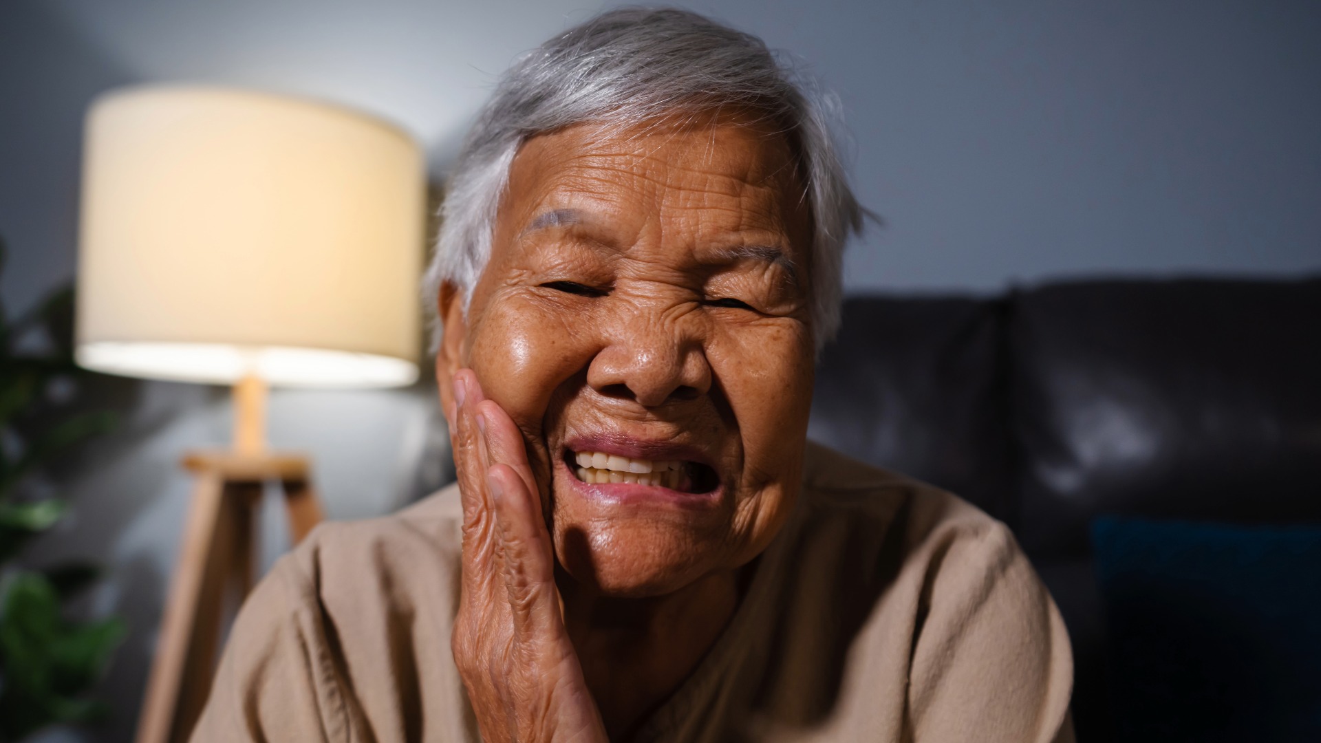 A senior woman holding her mouth in pain