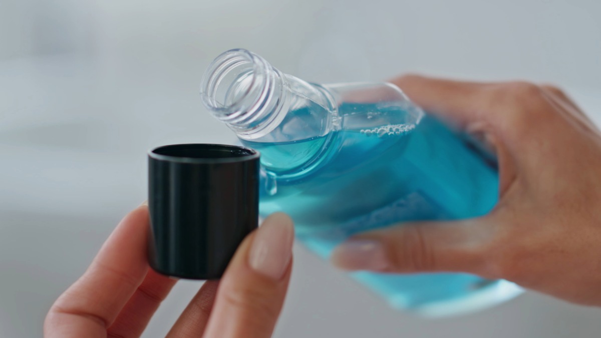 Someone pouring mouthwash into a cap