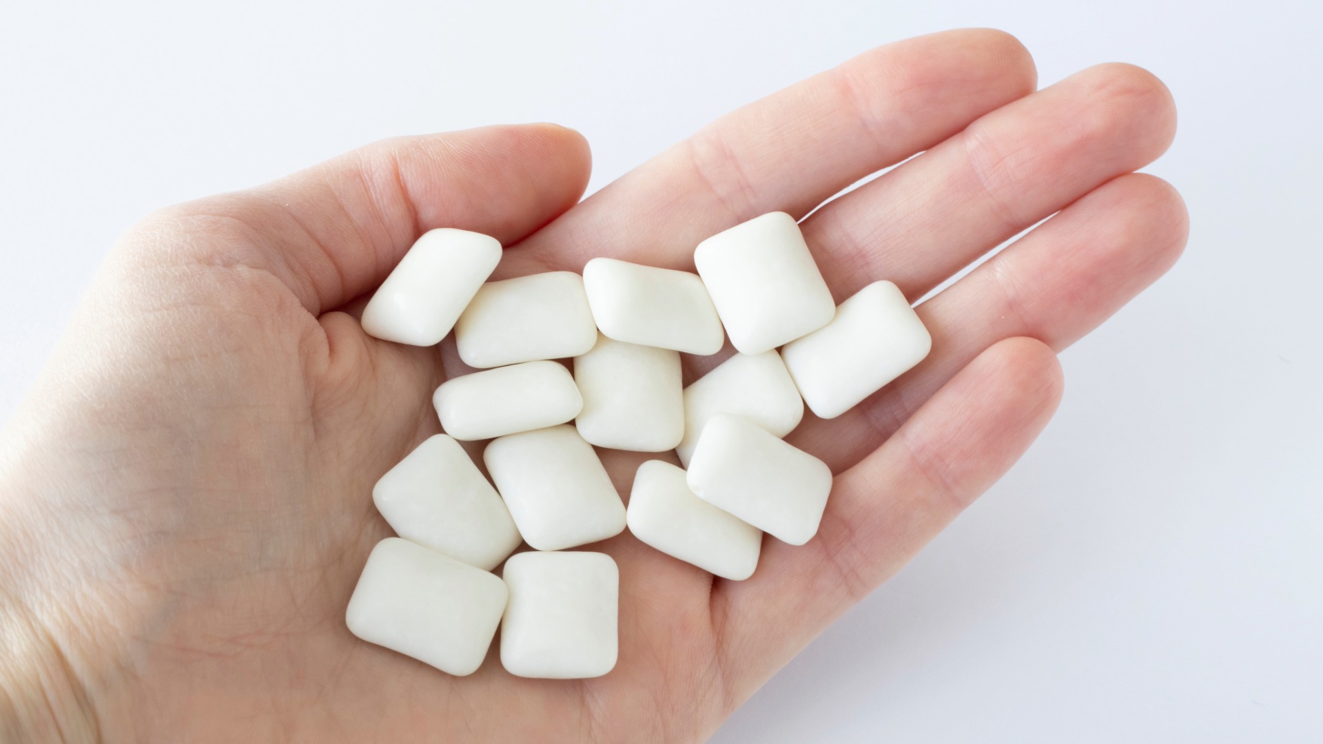A hand holding several pieces of sugarfree gum up to the camera