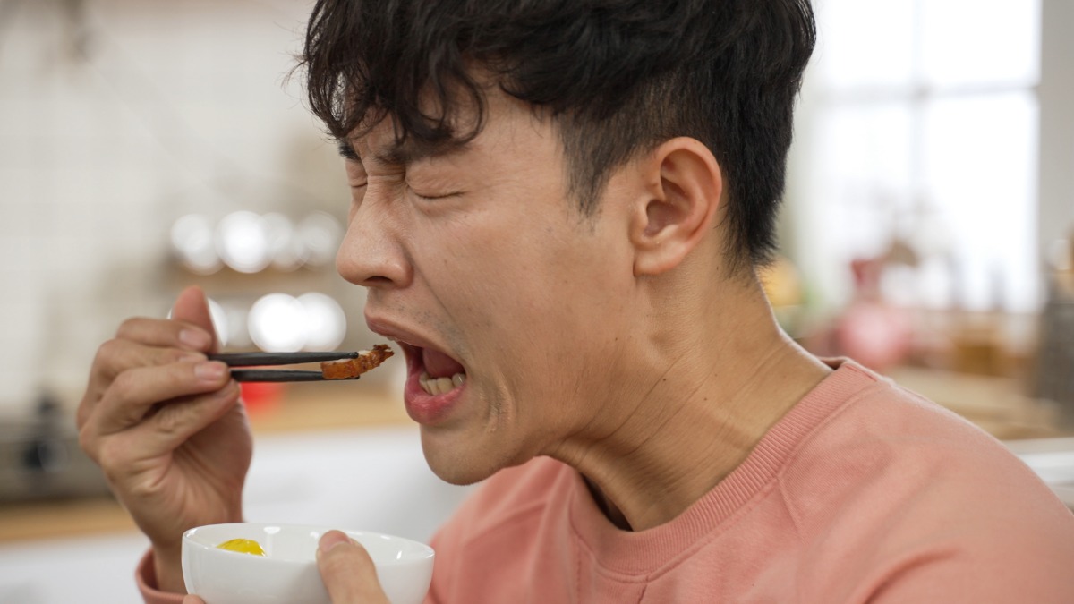 A man grimacing as he eats spicy food