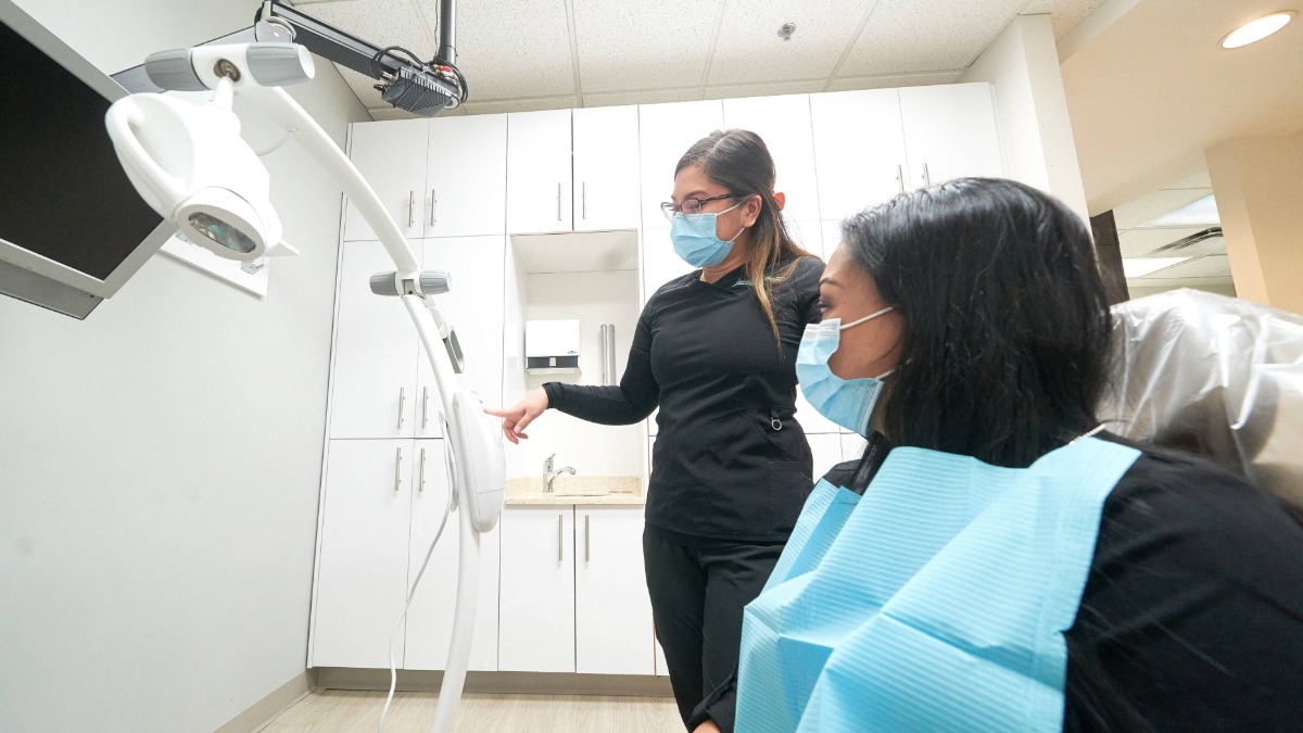 A dental professional explaining something to a patient in a dentist's chair