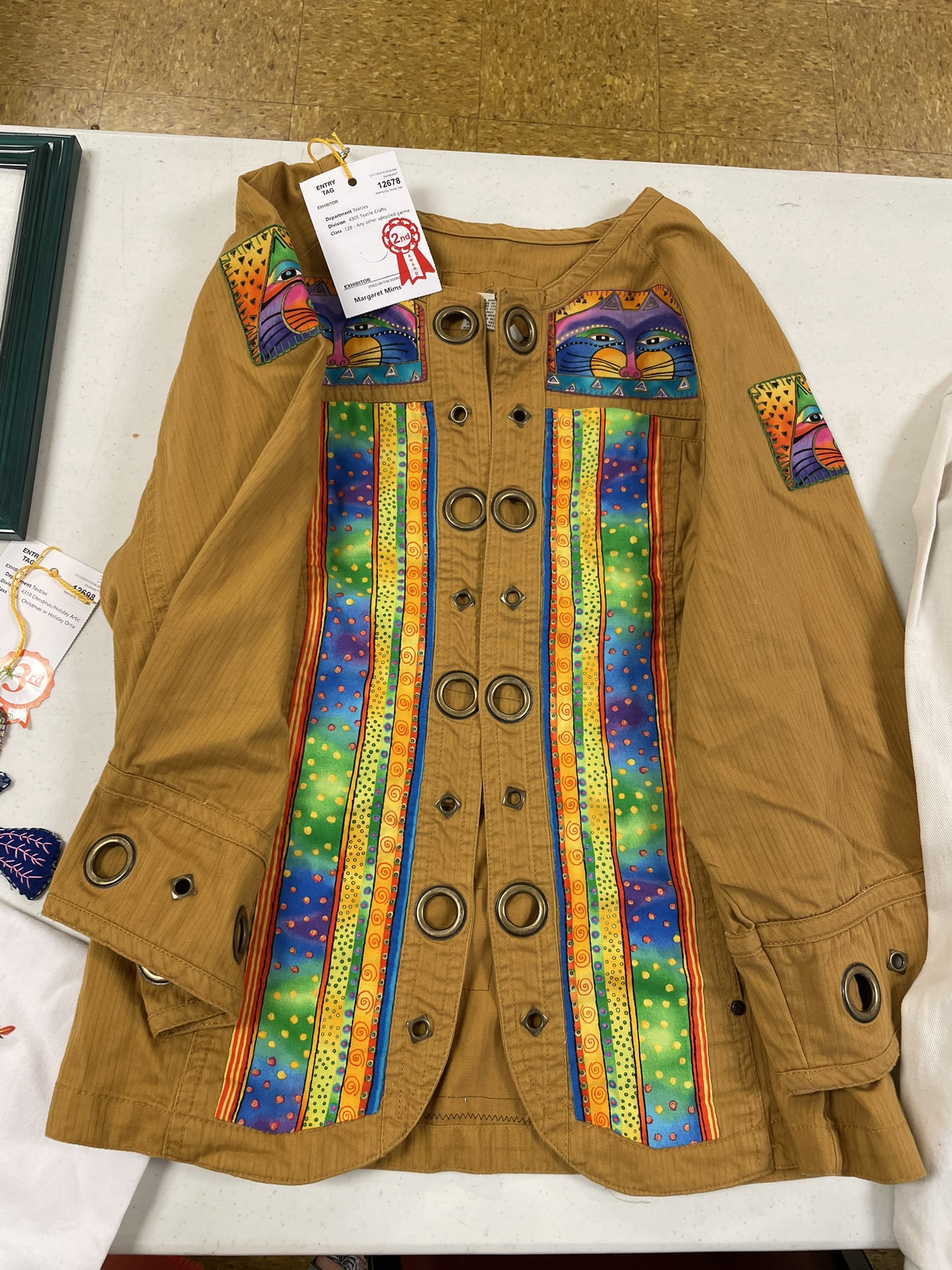 Tan jacket embellished with rainbow fabric panels and cat appliques