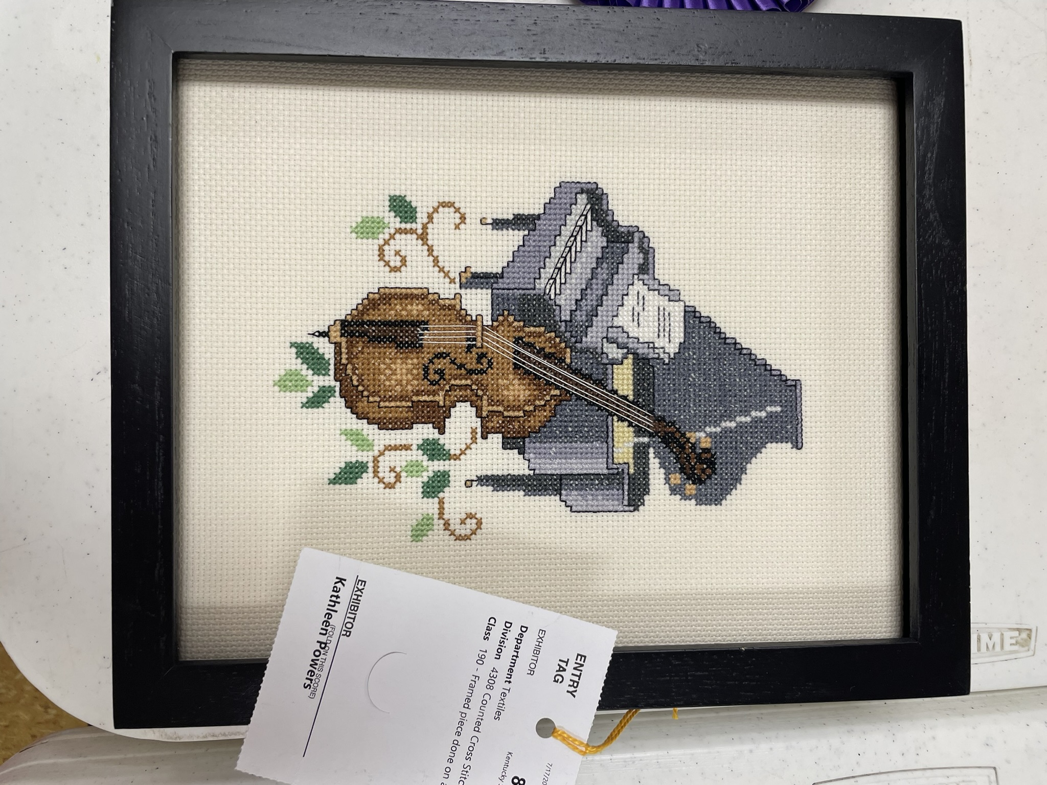 Framed cross stitch of a violin and piano