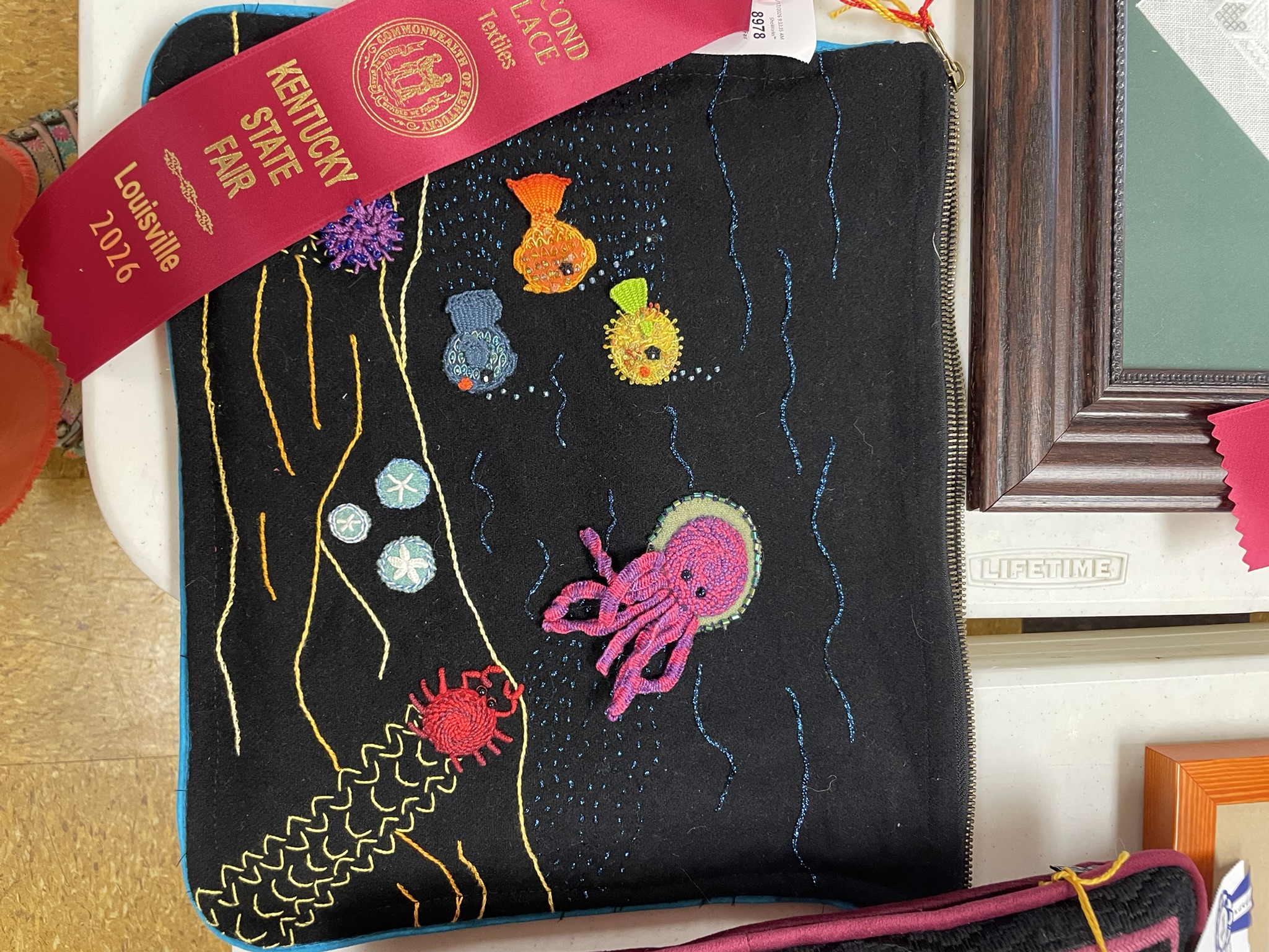 Black embroidered panel with jellyfish and sea creatures, second place ribbon