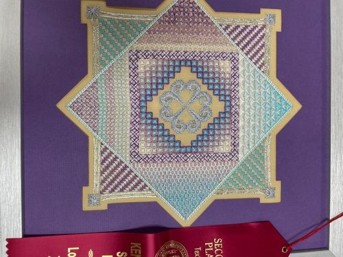 Blackwork star design in purple, teal and gold with a second place ribbon
