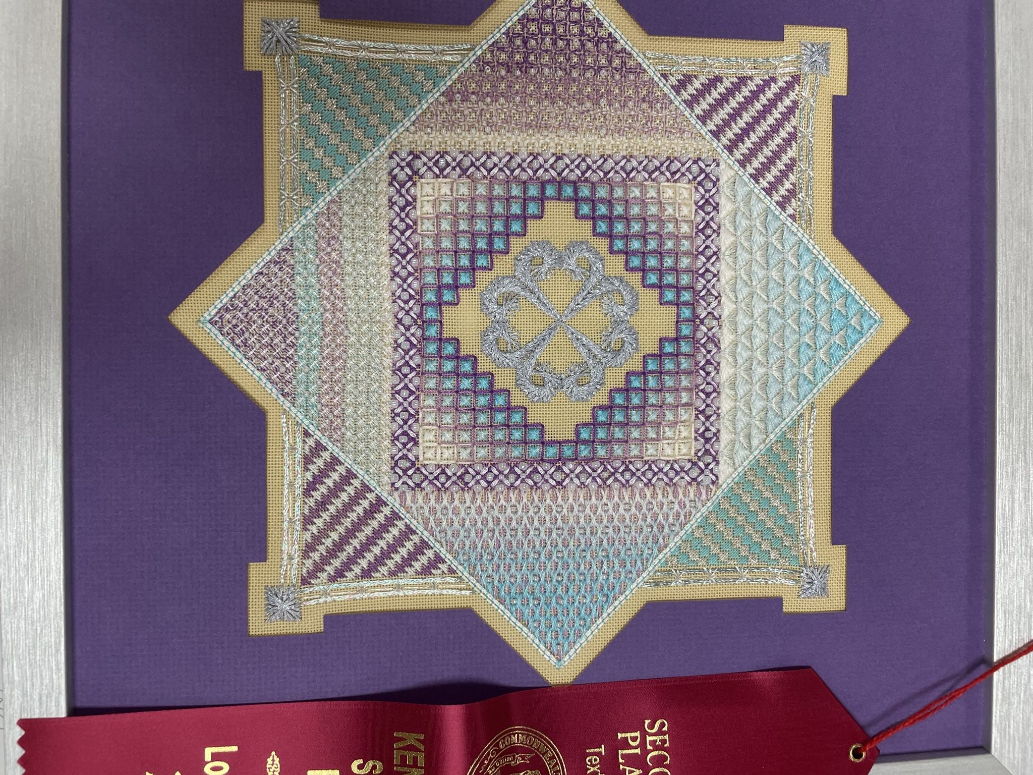Blackwork star design in purple, teal and gold with a second place ribbon