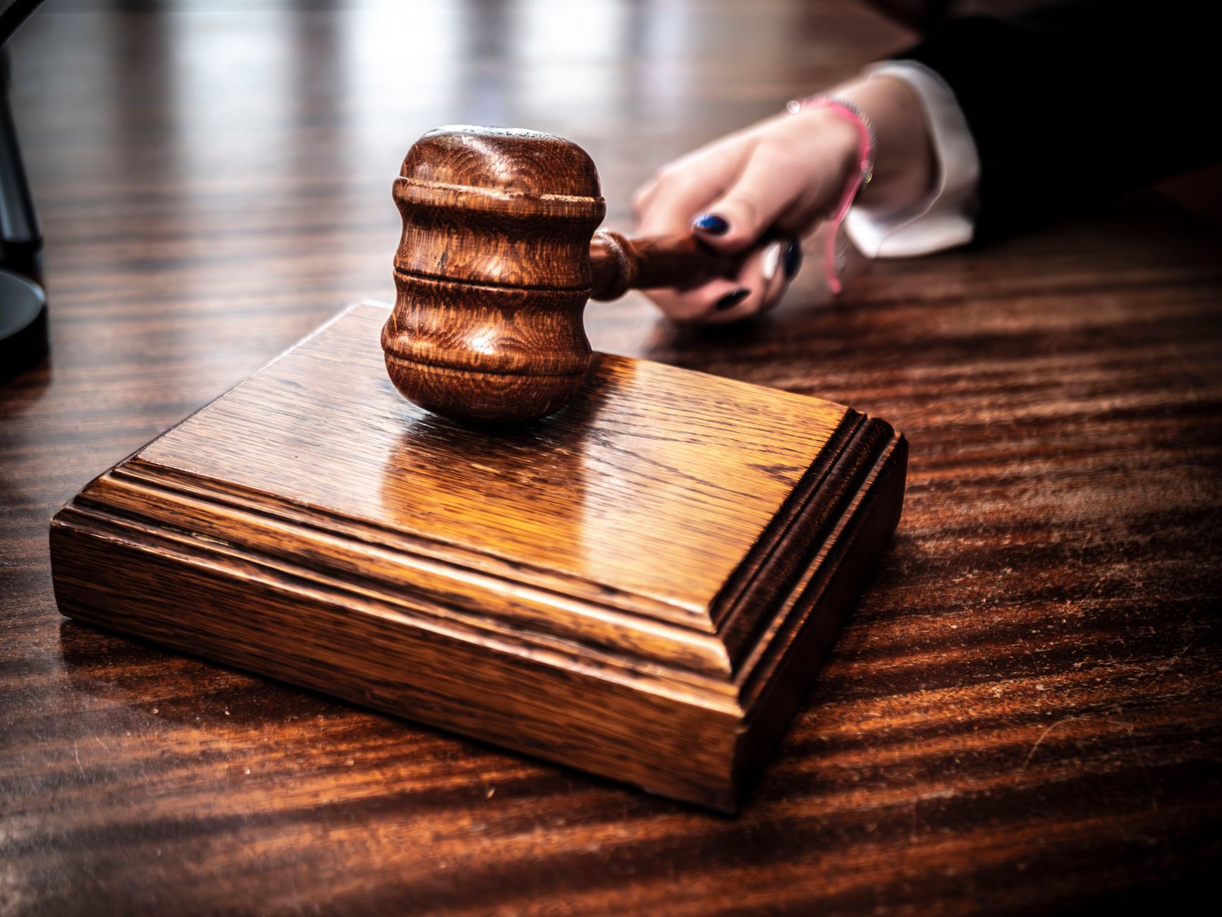 Close-up of a wooden gavel held by hand on a courtroom desk, symbolising judicial leaders exploring AI assistance for judicial tasks in Australia