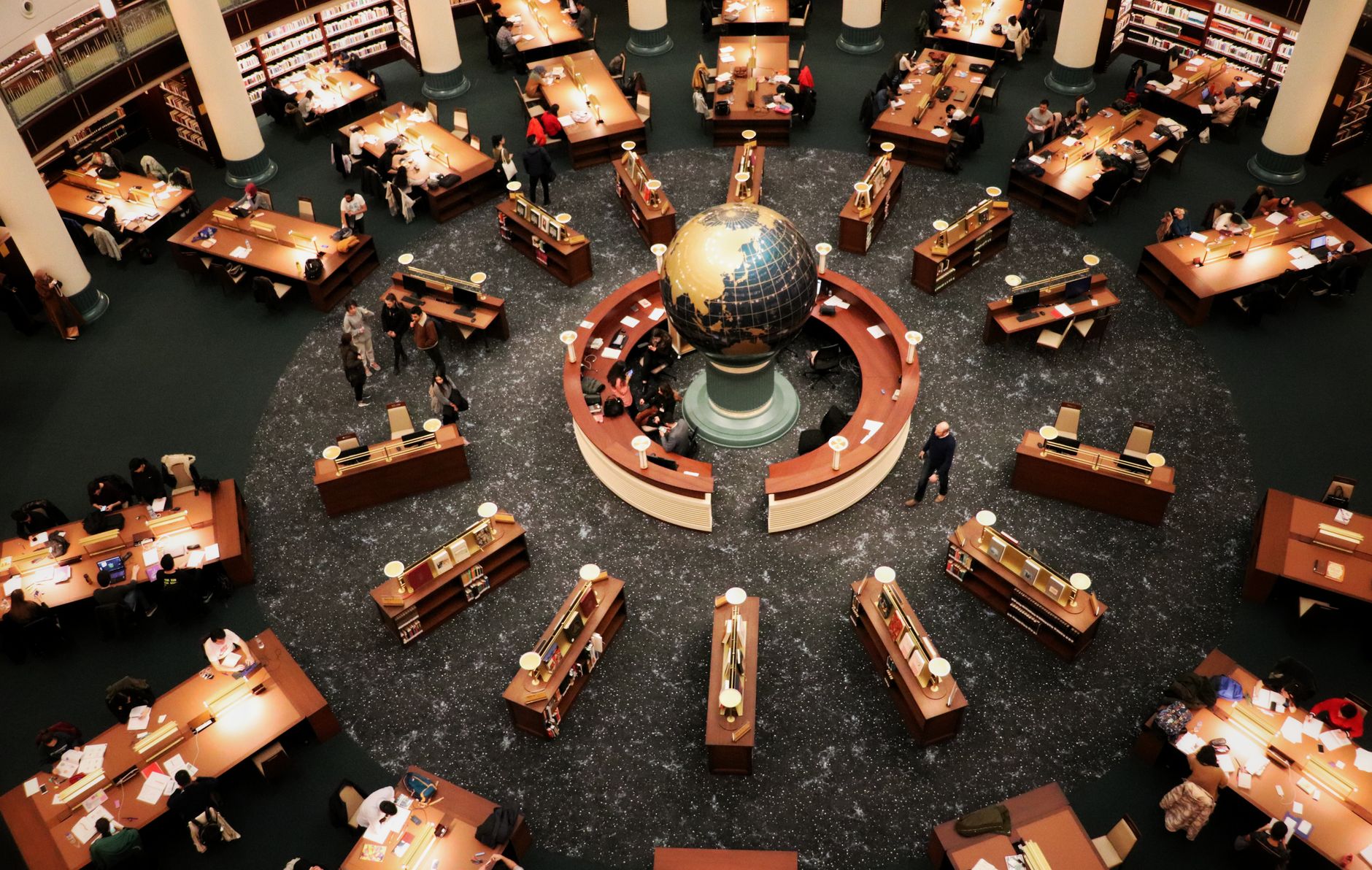 Busy library interior with a large globe and people working at wooden tables, illustrating research into causation defences under the Civil Liability Acts.