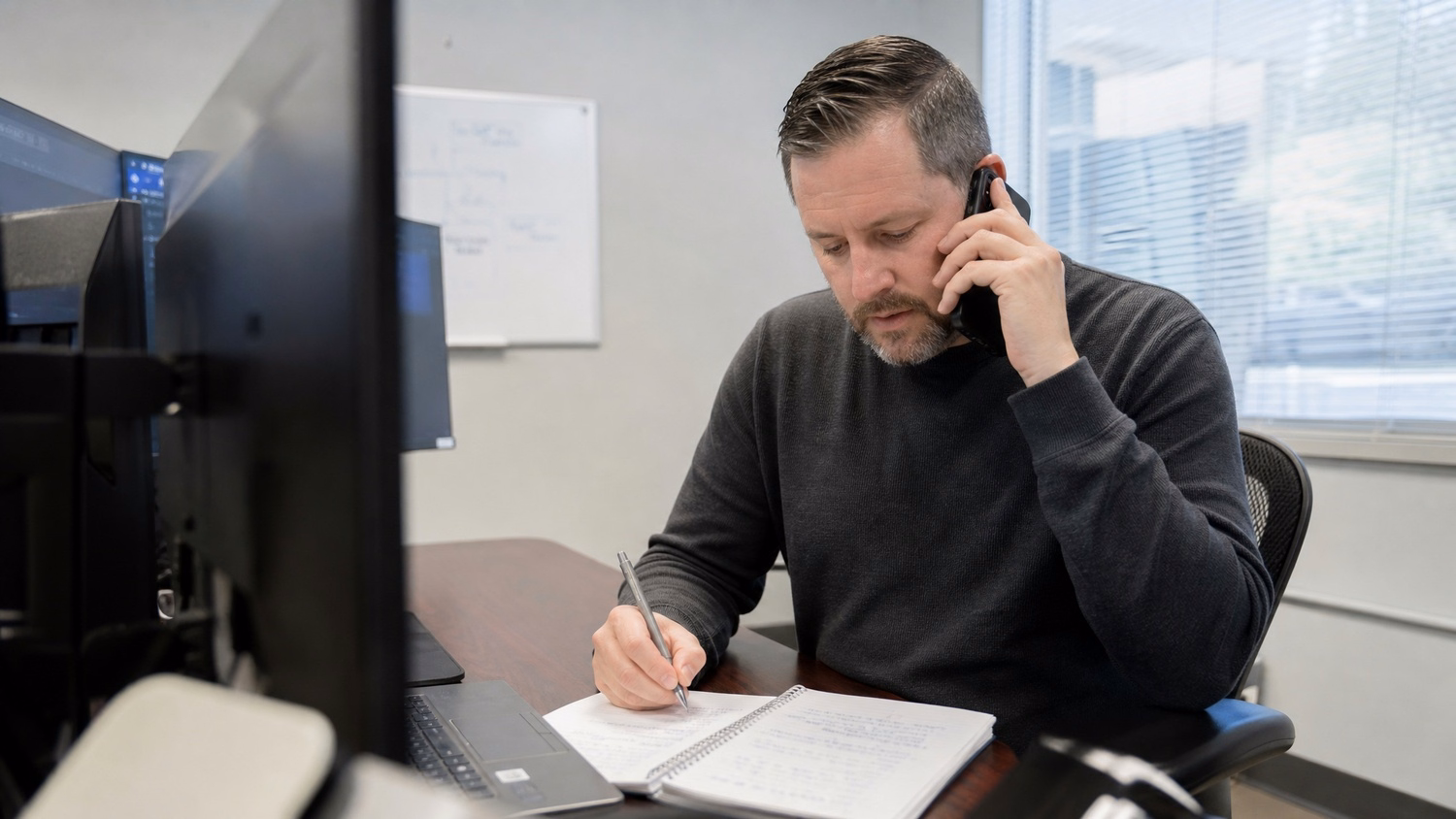 PHONE CALL AT DESK An IT professional one person at a desk with phone to one