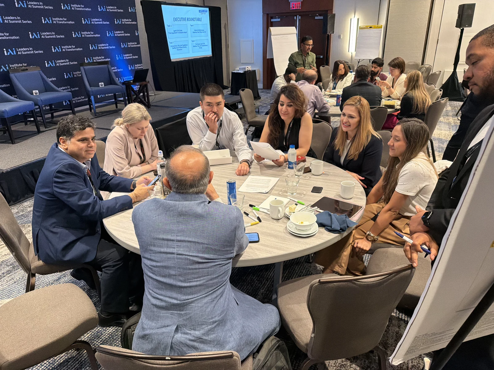 Executives comparing discussion questions at a Boston Leaders in AI summit roundtable.