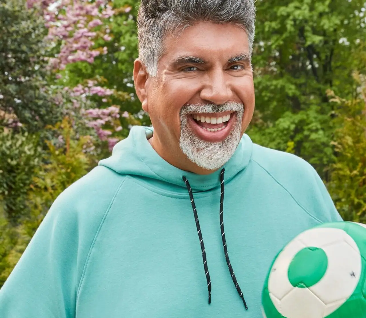 WeightWatchers member August in a hoody, holding a volleyball and smiling at the viewer. 