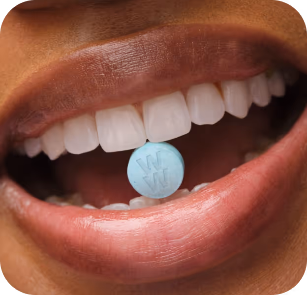 woman smiling with weight loss pill in her mouth