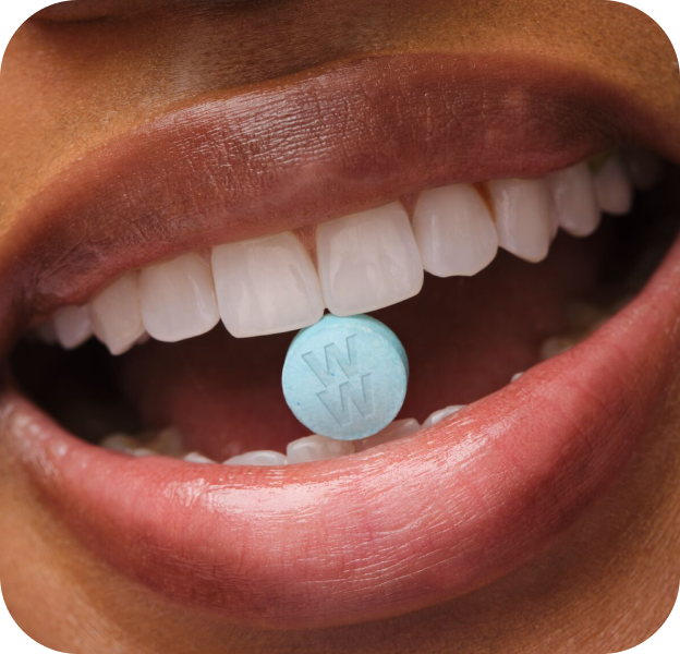 woman smiling with weight loss pill in her mouth