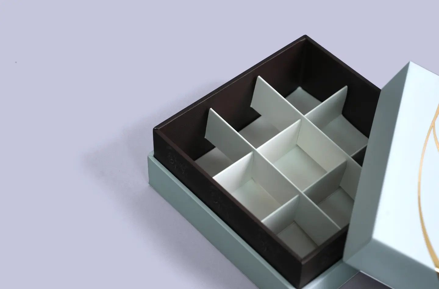 Detail shot of luxury chocolate telescopic rigid box with gold foil embossing and exposed nine-compartment paper insert