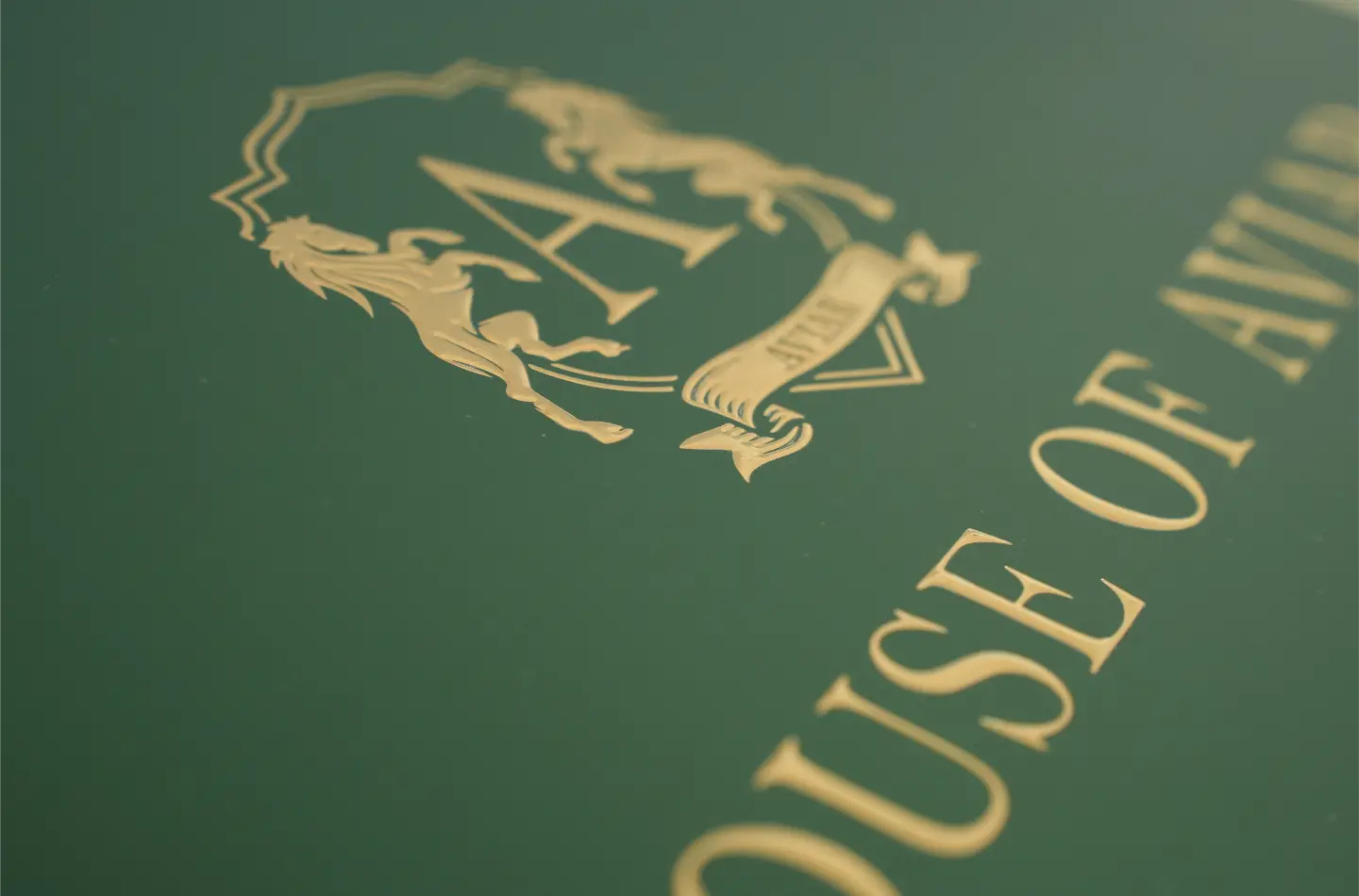 Close-up texture shot showing luxury gold hot stamping on a custom green rigid two-piece box.