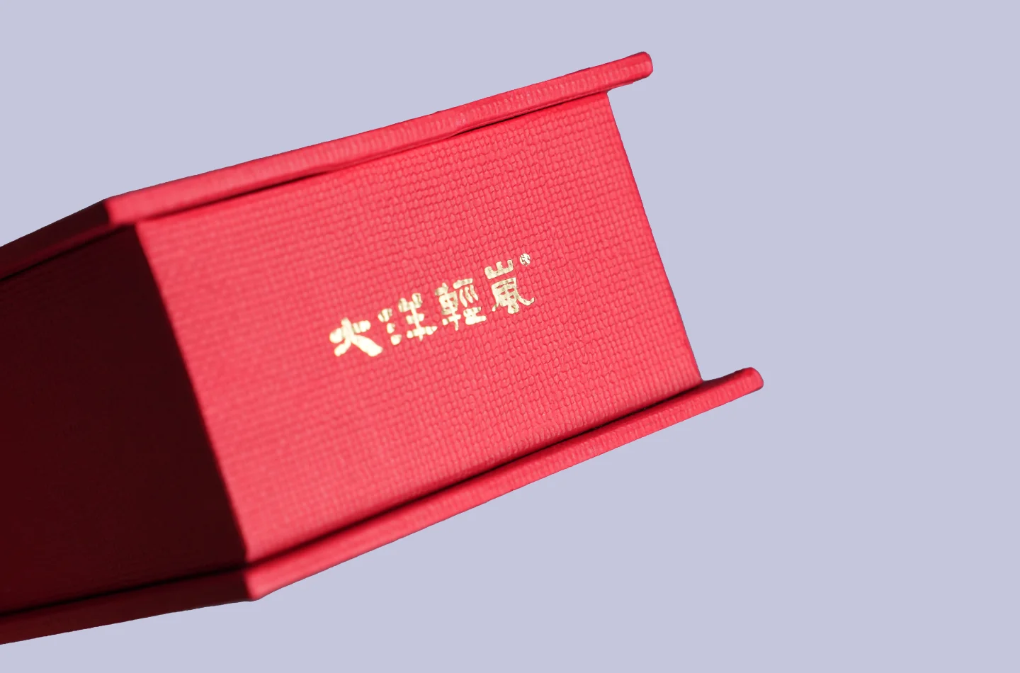 Detailed view of the gold foil decoration on the side of a red flip-top box