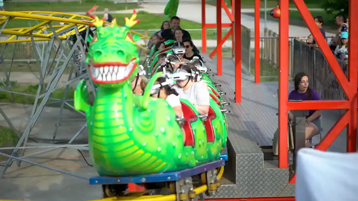 The dragon coaster train pulls in, the dragon's head first, every rider wearing a VR headset