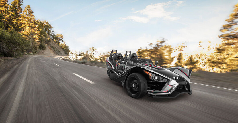 A Polaris Slingshot riding down a winding road, available to rent in Houston