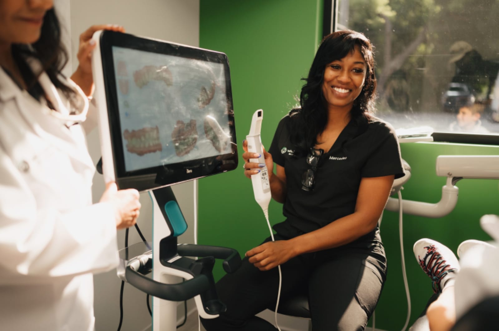 Dentist pointing at digital X-ray display showing patient oral imaging