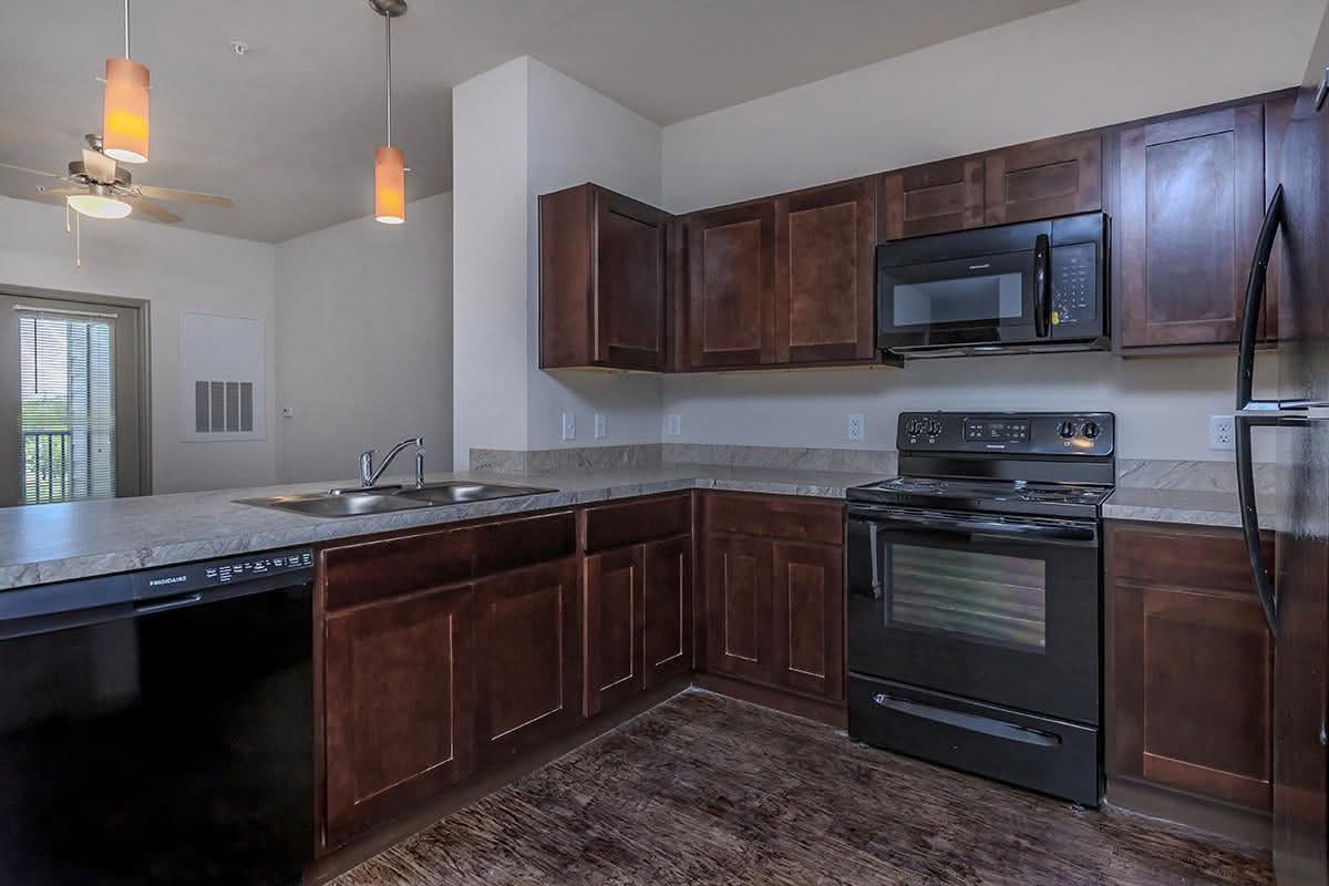 Kitchen with brown cabinets and black appliances 