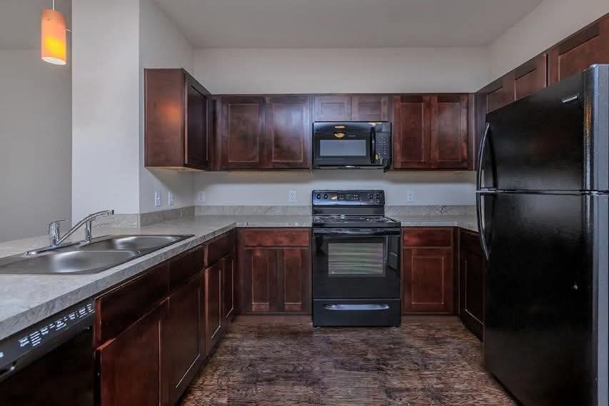 Kitchen with brown cabinets and black appliances 
