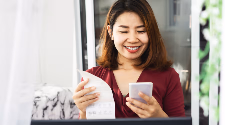 Customer at home checking her energy bill against her phone