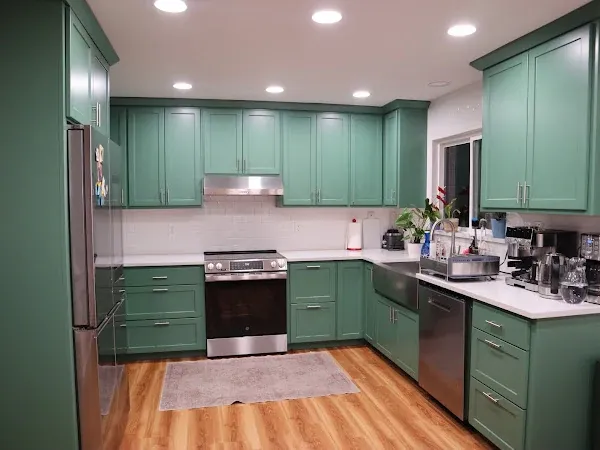 Kitchen with green cabinets, white countertops, and wood flooring