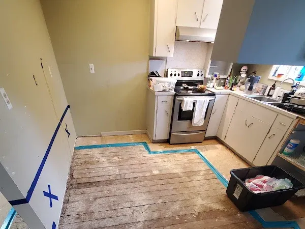 Kitchen renovation with exposed wood subfloor and white cabinets