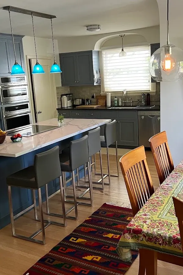 Kitchen with an island, dark cabinets, stainless appliances, and blue pendant lights
