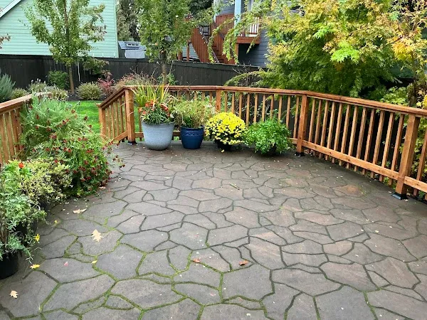 Stamped-concrete patio enclosed by wood railings with potted plants