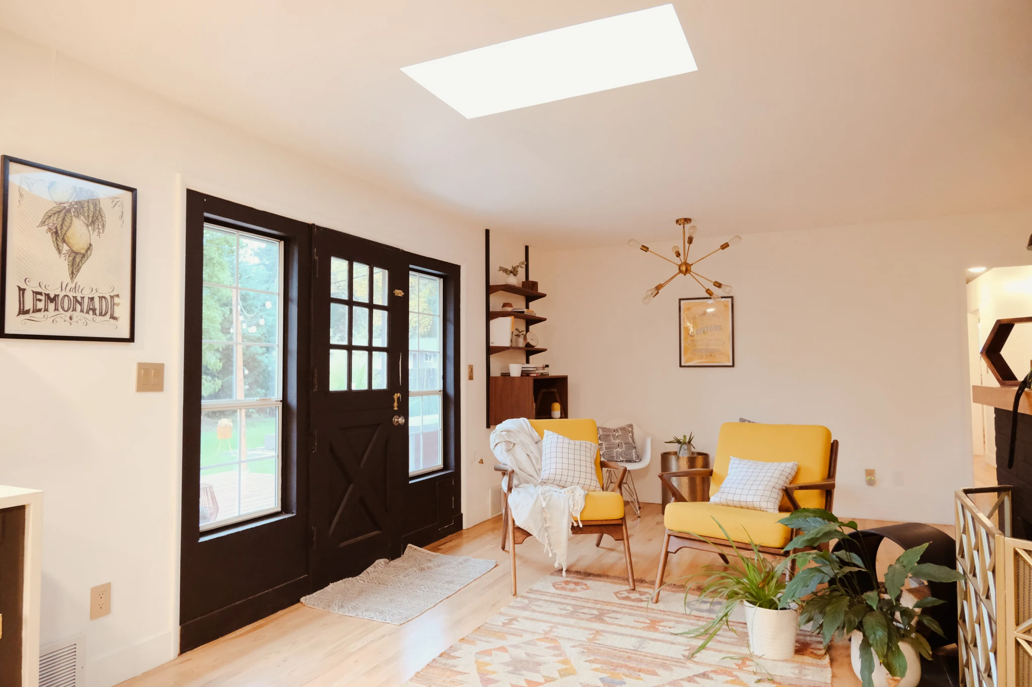 Sunlit living nook with yellow chairs, a skylight, and glazed doors opening to the garden.