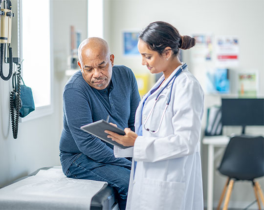Doctor writing on a clipboard while a patient sits on a table in a doctors office