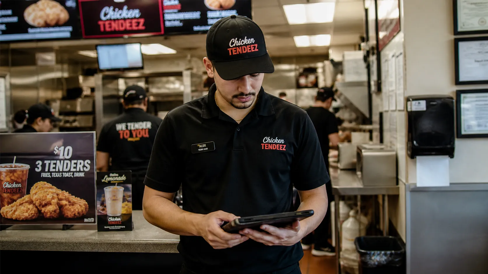 A fast service franchise worker at the front counter completing a checklist on a tablet