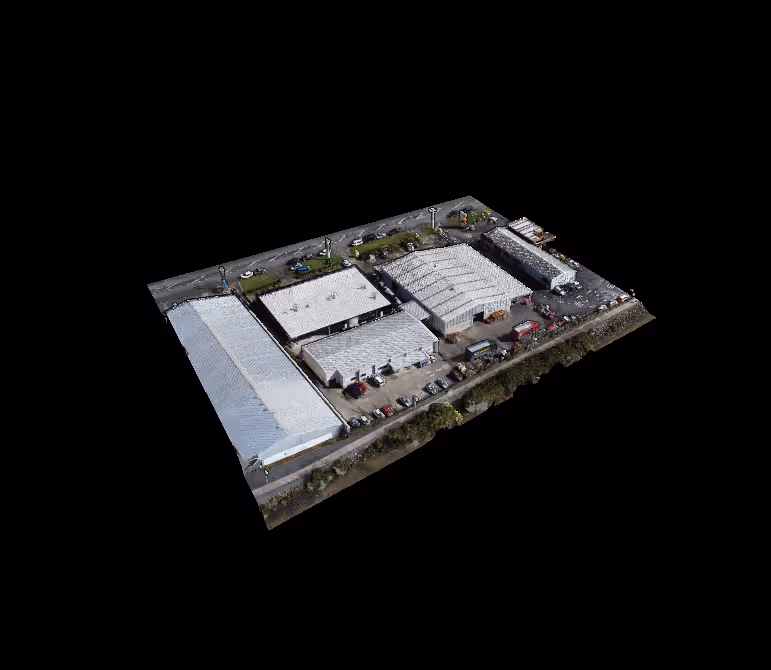 Aerial view of a commercial complex with multiple white-roofed buildings, parking spaces, and vehicles.