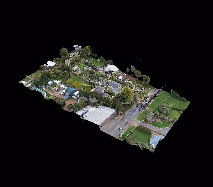 Aerial view of a residential area with houses, gardens, trees, and a main road crossing through it.
