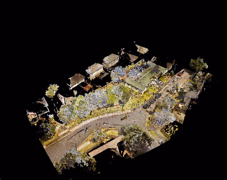 Aerial view of a residential street lined with trees and houses, featuring a curved road and several parked cars.