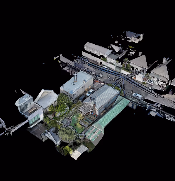 Aerial view of a residential area showing multiple houses, roofs, gardens, driveways, and parked cars.